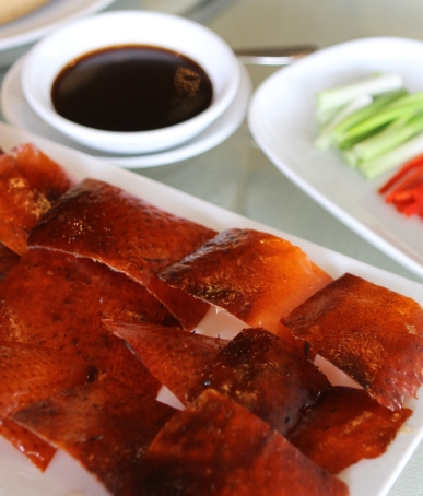 peking duck skin with dipping sauce and some side vegetables